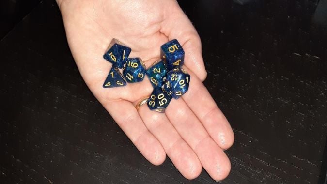 Hand holding blue and gold dice
