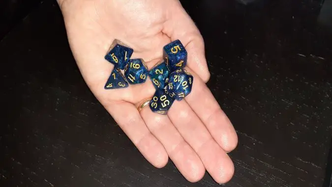 Hand holding blue and gold dice