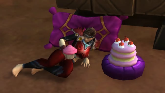 A woman stares lovingly at a pink cupcake. A pink and purple cake sits beside her.